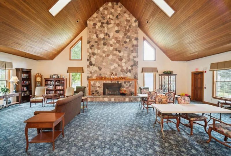 Great room with vaulted wood ceiling and large stone fireplace at Adava Care Hartland in Hartland, WI