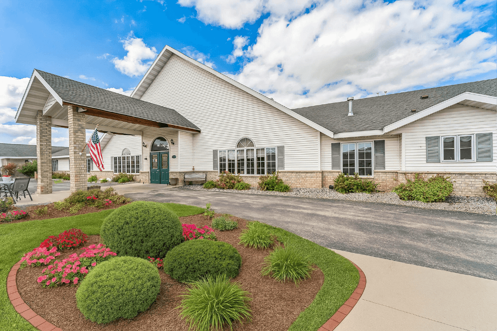 White building with American flag and landscaped garden.