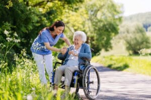 Caregiver assisting senior in wheelchair outdoors